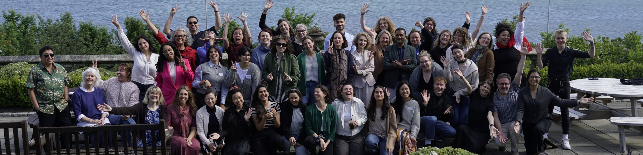 A group imagine of delegates on the Arts Health Research Intensive 2026. Behind the group of delegates is a view of the sea.